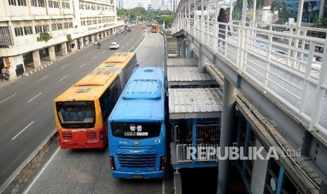 Bus Transjakarta menaikan dan menurunkan penumpang di halte bus Transjakarta. ilustrasi