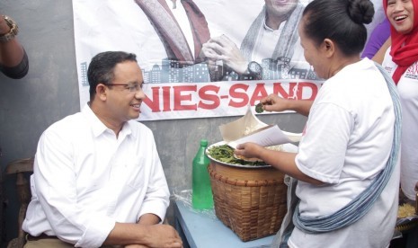 Cagub DKI Jakarta, Anies Baswedan, mencicipi pecel legendaris Sayijatinah (53) atau Bukde Tin saat blusukkan ke Pulogadung, Jakarta Timur, Selasa (10/1). 