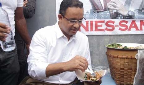 Cagub DKI Jakarta, Anies Baswedan, mencicipi pecel legendaris Sayijatinah (53) atau Bukde Tin saat blusukkan ke Pulogadung, Jakarta Timur, Selasa (10/1). 