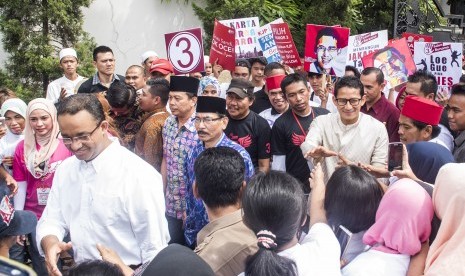 Calon Gubernur DKI Jakarta Anies Baswedan (kiri) dan pasangannya calon Wakil Gubernur Sandiaga S. Uno (kedua kanan) menyapa warga saat kampanye di Cilandak, Jakarta, Senin (19/12). 