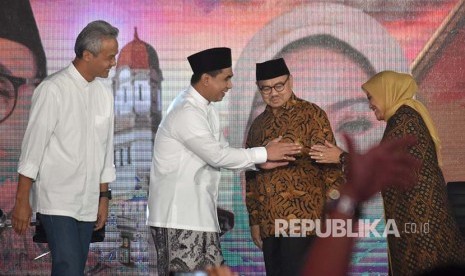 Calon gubernur Ganjar Pranowo (kiri) dan Sudirman Said (kedua kanan) menyaksikan calon wakil gubernur Taj Yasin (kedua kiri) dan Ida Fauzia (kanan) berjabat tangan. 