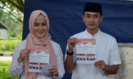 Calon Gubernur Jambi nomor urut dua Zumi Zola Zulkifli (kanan) bersama istri Sherrin Tharia (kiri) memperlihatkan lembaran surat suara sebelum menggunakan hak pilih pada pemilihan kepala daerah serentak di TPS 4, Kelurahan Rano, Muara Sabak Barat, Tanjung 