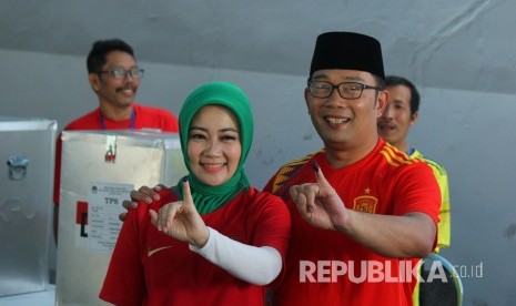 Calon Gubernur Jawa Barat Ridwan Kamil bersama istri Atalia Praratya menunjukan tinta di jari kelingking usai mencoblos dalam Pilkada Serentak 2018, di Tempat Pemungutan Suara (TPS) 21, Cigadung, Kota Bandung, Rabu (27/6).