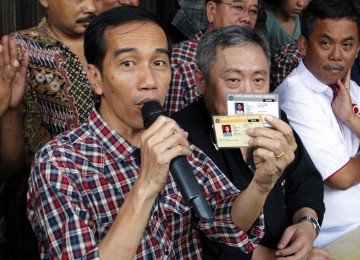 Calon Gubernur Joko Widodo memperlihatkan kartu sehat dan kartu pendidikan, di Jalan Gajah Mada-Hayam Wuruk, Ahad (1/3). (Republika/Adhi Wicaksono)