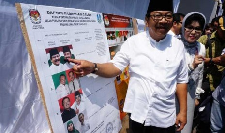 Calon Gubernur nomor urut ke-1, Soekarwo (kiri) didampingi istri, menunjuk foto dirinya usai menggunakan hak pilihnya dalam Pemilihan Gubernur (Pilgub) Jawa Timur 2013 di TPS 26, Kecamatan Manyar Sabrangan, Surabaya, Jatim, Kamis (29/8).