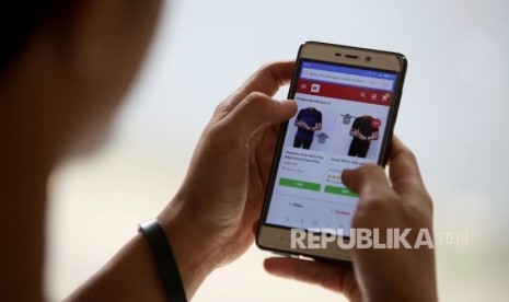 Calon pembeli melihat koleksi fashion terbaru mealui salah satu gerai E-Commerce melalui telfon genggamnya di Jakarta, Senin (31/7).