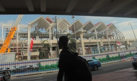 Calon penumpang berjalan dengan latar belakang pembangunan stasiun kereta tanpa masinis/automated people mover system (APMS) atau skytrain di Bandara Soetta, Tangerang, Banten, 25 Agustus 2017. Skytrain yang menghubungkan Terminal 1, 2, dan 3 di Bandara Soetta itu diharapkan akan lebih memberikan kemudahan akses antar terminal bagi penumpang maskapai penerbangan. 