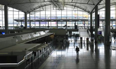 Calon penumpang berjalan di Bandara Hong Kong yang kosong pada Jumat (18/2/2022). Pemimpin Hong Kong Carrie Lam mengatakan akan membuka kembali penerbangan dan mengurangi durasi karantina penumpang luar negeri.