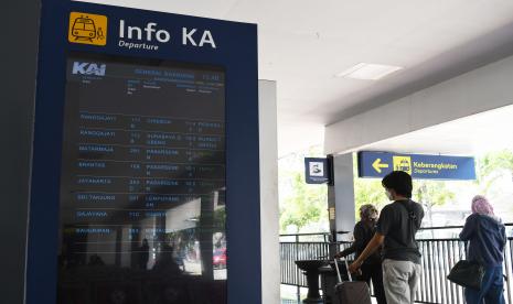 Calon penumpang melintas di dekat papan informasi di Stasiun Kereta Api (KA) Madiun, Jawa Timur (ilustrasi). KAI kembali membolehkan anak berusia di bawah 12 tahun untuk menggunakan kereta jarak jauh.