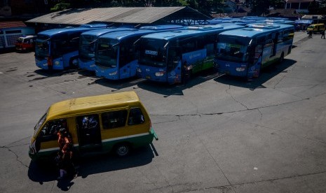 Calon penumpang melintas di depan bus Trans Metro Bandung (TMB) di Terminal Leuwi Panjang, Bandung, Jawa Barat, Rabu (3/4/2019).