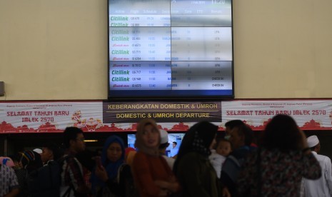 Calon penumpang mengamati layar informasi penerbangan di terminal keberangkatan domestik 1A Bandara Internasional Juanda Surabaya, Sidoarjo, Jawa Timur, Kamis (7/2/2019).