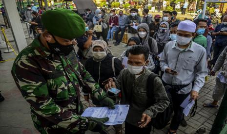 Calon penumpang menunjukan surat tanda registrasi pekerja (STRP) atau surat tugas kepada anggota TNI di Stasiun Bogor, Kota Bogor, Jawa Barat.