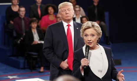 Calon presiden AS Donald Trump berdiri di belakang rivalnya Hillary Clinton saat debat kedua di Washington University, St Louis, Ahad, 9 Oktober 2016.