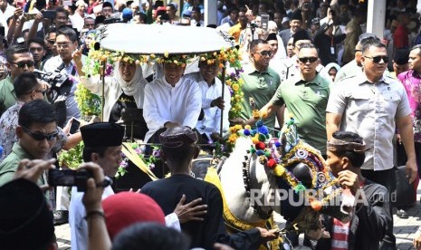 Calon Presiden nomor urut 01 Joko Widodo (tengah) didampingi putri almarhum KH Abdurrahman Wahid, Yenny Wahid (kiri) menaiki delman menuju lokasi Deklarasi Akbar Ulama se-Madura untuk Jokowi-Maruf di Bangkalan, Madura, Jawa Timur, Rabu (19/12/2018). 