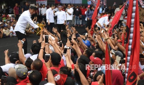 Calon Presiden petahana nomor urut 01 Joko Widodo (kiri) berjabat tangan dengan pendukung saat kampanye terbuka di Banyuwangi, Jawa Timur, Senin (25/3/2019). 