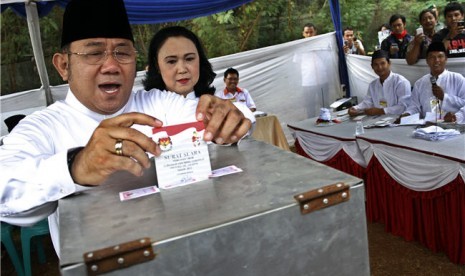 Calon Wakil Gubernur DKI Jakarta, Nachrowi Ramli atau Nara (kiri), bersama isteri Alfina Evi Maria (kedua kiri) memberikan hak suaranya di TPS 029 Kelurahan Batu Ampar, Kramat Jati, Jakarta Timur, Kamis (20/9). 