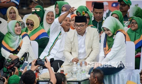 Calon Wakil Gubernur Jawa Barat nomor urut satu Uu Ruzhanul Ulum (kedua kiri) berusaha mengambil burung yang hinggap di kepala Calon Gubernur Jawa Barat nomor urut satu Ridwan Kamil (kedua kanan) saat kampanye akbar pasangan calon Rindu di Lapangan Tegalega, Bandung, Jawa Barat, Sabtu (23/6). 