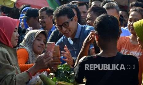 Calon Wakil Presiden nomor urut 02 Sandiaga Salahuddin Uno (tengah) melayani warga yang ingin berfoto bersamanya, saat berkunjung di Pasar Wonodri Semarang, Jawa Tengah, Senin (24/9). 