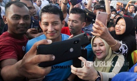 Calon Wakil Presiden nomor urut 02 Sandiaga Salahudin Uno (kedua kiri) melayani permintaan swafoto dari pendukungnya usai lari pagi mengelilingi waduk Lhokseumawe di Aceh, Ahad (3/2/2019).