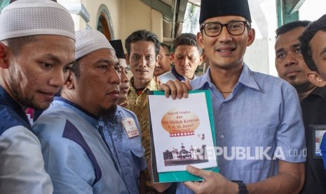 Calon Wakil Presiden nomor urut 02 Sandiaga Uno (kedua kanan) menunjukan buku sejarah Syech Baing Yusuf usai berziarah ke makam R. H.M. Joesof atau yang dikenal dengan Syech Baing Yusuf saat berkampanye di Purwakarta, Jawa Barat, Rabu (14/11/2018).