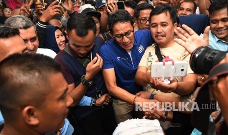 Calon Wakil Presiden Sandiaga Uno (tengah) menyapa pengunjung dan pedagang ketika berkunjung ke Pusat Grosir Surabaya (PGS), Surabaya, Jawa TImur, Ahad (21/10/2018). 