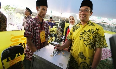  Calon wali Kota Bandung, Ridwan Kamil beserta istri memasukan surat suara setelah melakukan pencoblosan di TPS 19, Jalan Cigadung Selatan VII, Bandung, Ahad (23/6). (Republika/Edi Yusuf)