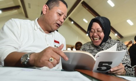 Calon Walikota Surabaya Tri Rismaharini (kanan) dan pasangannya calon Wakil Walikota Surabaya Wisnu Sakti Buana (kiri) membaca buku yang dibagikan KPK ketika mengikuti pembekalan dan deklarasi calon kepala daerah dan penyelenggara Pilkada Jatim di Unesa, S