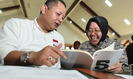 Calon Walikota Surabaya Tri Rismaharini (kanan) dan pasangannya calon Wakil Walikota Surabaya Wisnu Sakti Buana (kiri) membaca buku yang dibagikan KPK ketika mengikuti pembekalan dan deklarasi calon kepala daerah dan penyelenggara Pilkada Jatim di Unesa, S