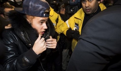 Canadian musician Justin Bieber is swarmed by media and police officers as he turns himself in to city police for an expected assault charge, in Toronto, on Wednesday, Jan. 29, 2014. 