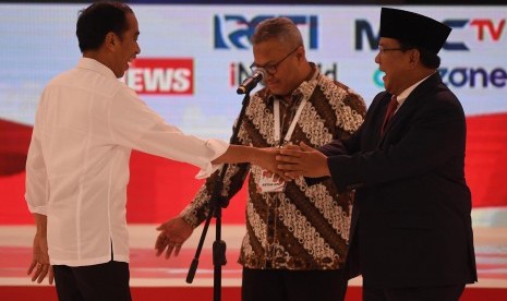 Capres nomor urut 01 Joko Widodo (kiri) dan Capres nomor urut 02 Prabowo Subianto (kanan) bersiap memulai debat capres 2019 disaksikan Ketua KPU Arief Budiman (tengah) di Hotel Sultan, Jakarta, Ahad (17/2/2019).