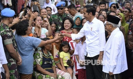 Capres petahana Joko Widodo (kedua kanan) dan cawapres Ma'ruf Amin (kanan) menyapa warga usai menyampaikan pidato kemenangannya sebagai Presiden Republik Indonesia periode 2019-2024 di Kampung Deret, Tanah Tinggi, Johar Baru, Jakarta Pusat, Selasa (21/5/2019).