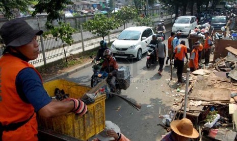  Sejumlah petugas kebersihan membersihkan sampah yang berserakan di pinggir Jalan I Gusti Ngurah Rai, Klender, Jakarta Timur, Selasa (4/3). (foto : Raisan Al Farisi)