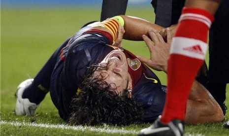 Carles Puyol, bek Barcelona, mengerang kesakitan akibat mengalami cedera siku saat menghadapi Benfica di laga Grup G Liga Champions di Stadion Luz, Lisbon, Selasa (2/10). 