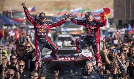 Carlos Sainz (R) dan co-driver Lucas Cruz berpose setelah menjuarai Reli Dakar 2020 kategori mobil.