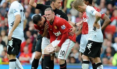 CEDERA EMPAT PEKAN. Striker Manchester United, Way Rooney (tengah) meringis kesakitan karena pahanya robek dalam laga lanjutan Liga Primer Inggris, Sabtu (25/8). Cedera itu diprediksi membuat Rooney absen selama empat pekan.