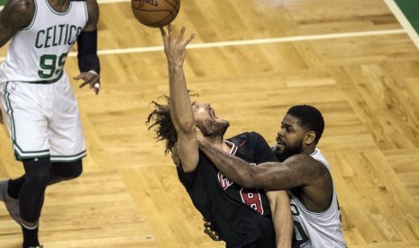 Center Chicago Bulls, Robin Lopez (tengah) berebut bola dengan dua pemain Boston Celtics pada laga playoff NBA, di TD Garden, Selasa (18/4).