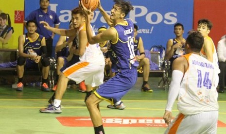 Center Satria Muda Anggi Arizki (biru) berusaha memasukkan bola ke basket saat menghadapi Pelita Jaya, Sabtu (11/10).