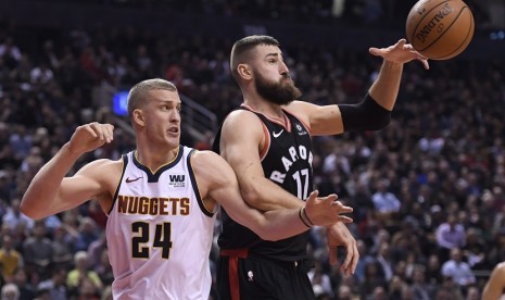 Center Toronto Raptors Jonas Valanciunas (17) mengontrol bola dengan adangan pemain Denver Nuggets, Mason Plumlee (24) dalam pertandingan NBA di Toronto, Selasa (4/12). 