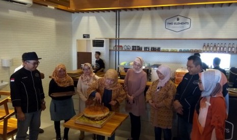   CEO Elcorps Elidawati (tengah) didampingi istri Bupati Purwakarta, Anne Ratna Mustika (keempat dari kanan) dan COO Elfood Andrin(paling kiri) melakukan pemotongan burger raksasa dalam soft opening Cafe Two Elements di Purwakarta, Ahad (10/12). Foto: Rachmat Santosa Basarah/Republika