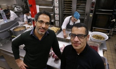 Chefs Yotam Ottolenghi (left) and Sami Tamimi pose for the photographer at their company's bakery in London. One chef is Israeli, the other a Palestinian.   