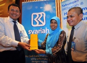 Chief of Retail Banking BRI Syariah, Khairullah, menyerahkan hadiah satu kilogram emas kepada nasabah pemenang hadiah hujan emas BRI Syariah, Chasnidar, didampingi Pimpinan Cabang BRI Syariah Yogyakarta, Halomon Marpaung, di Jakarta, Kamis (18/8). 