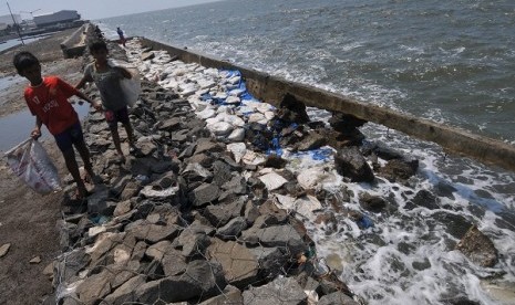 Children pass the  burst dyke in Muara Baru, Jakarta. Government will build giant sea wall ahead of plan in 2014 instead of 2020. (illustration)