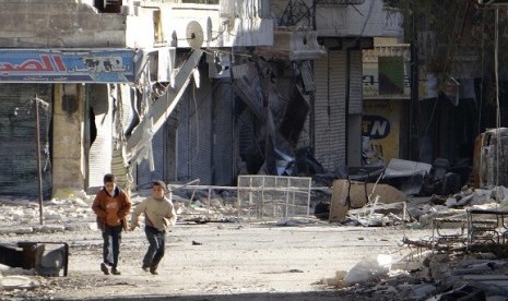 Children run along a street damaged by what activists said was a Syrian Air Force air strike in the Aleppo district of Salaheddine December 5, 2012. Picture taken December 5, 2012.   