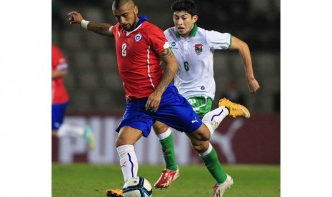 Chile's Arturo Vidal (L) and Bolivia's Pedro Azogue fight for the ball during their international friendly soccer match in Coquimbo city, north of Santiago, October 14, 2014. 