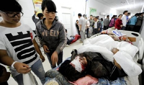 Chinese women look at a person injured by an earthquake resting on a bed at a hospital in Minxian county in Dingxi city in northwest China's Gansu province on Monday, July 22, 2013. 