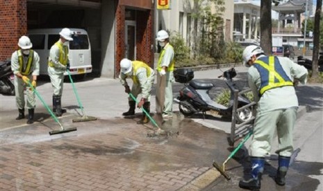 City officials wearing masks clean the pavement covered by ash Monday morning, Aug. 19, 2013 after the Sakurajima volcano erupted Sunday afternoon in Kagoshima, on the southern Japanese main island of Kyushu. 