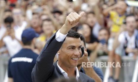 Cristiano Ronaldo memberi hormat kepada para penggemarnya saat ia tiba untuk menjalani pemeriksaan medis di stadion Juventus di Turin, Italia, Senin (16/7).