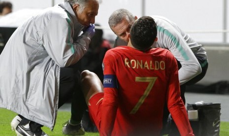 Cristiano Ronaldo mendapatkan perawatan dari tim medis Portugal saat menderita gangguan otot dalam laga kontra Serbia.