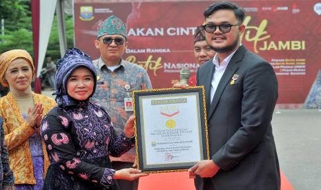 Customer Relations Manager Museum Rekor-Dunia Indonesia Lutvi Syah Pradana (kanan) menyerahkan piagam MURI kepada Ketua TP PKK Provinsi Jambi Hesnidar Haris (kedua kiri) usai pelaksanaan Parade Batik di Telanaipura, Jambi, Kamis (29/9/2022). Kegiatan yang juga dilaksanakan serentak oleh pemerintah daerah tingkat kota/kabupaten se-Provinsi Jambi dengan melibatkan 10 ribu lebih ASN itu mendapatkan rekor Museum Rekor-Dunia Indonesia (MURI) untuk kategori Mengenakan Busana Batik Etnik Serentak oleh Aparatur Sipil Negara terbanyak. 