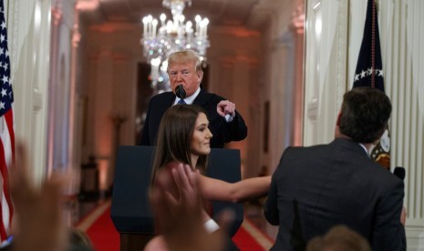 Dalam foto yang diambil pada 7 November 2018 ini, Presiden AS Donald Trump menyaksikan seorang pembantu Gedung Putih mengambil mikrofon dari wartawan CNN Jim Acosta saat konferensi pers. CNN menuntut Trump untuk membuka kembali akses Acosta ke Gedung Putih.